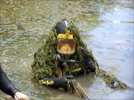 Diver emerging from water covered in thick cabomba weed