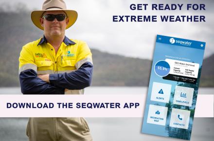 Seqwater ranger standing next to dam showing Seqwater app