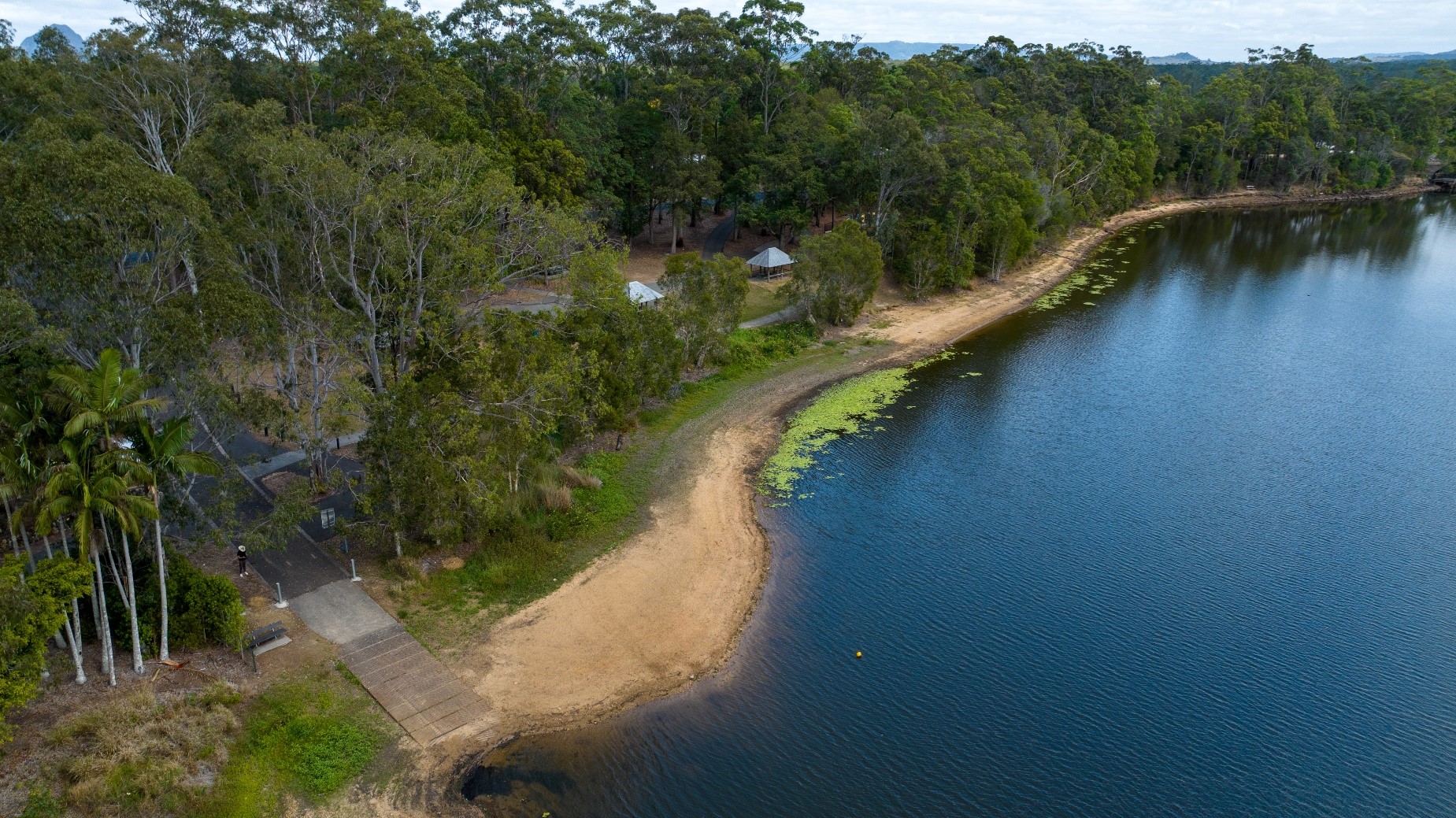 An aerial shot of a boat ramp and foreshore area leading into a blue lake