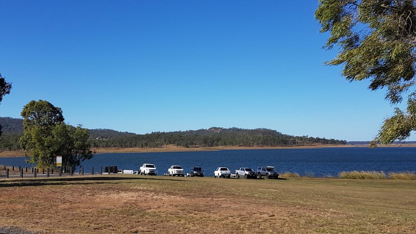 A line of cars parked at the foreshore of Billies Bay, a recreation area at Lake Wivenhoe.