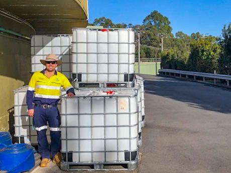 Seqwater Supply Operator Matthew Alderwick staning next to the intermediate bulk containers that are being auctioned off to provide funds to Beyond Blue
