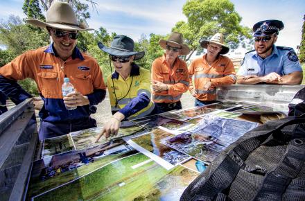 Representatives from Queensland Police, Seqwater and Powerlink overlook pictures and maps of the new fence.