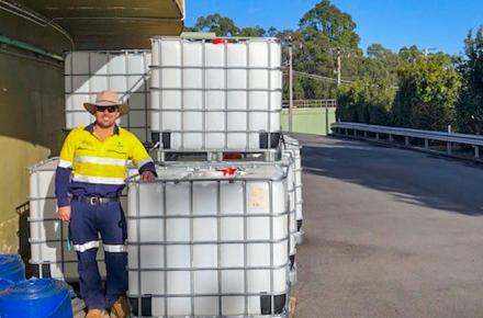 Seqwater Supply Operator Matthew Alderwick staning next to the intermediate bulk containers that are being auctioned off to provide funds to Beyond Blue