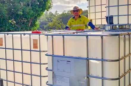 Seqwater Supply Operator Matthew Alderwick standing next to the intermediate bulk containers that are being auctioned off to provide funds to Beyond Blue