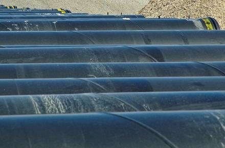 Row of black bulk water supply pipes ready for laying