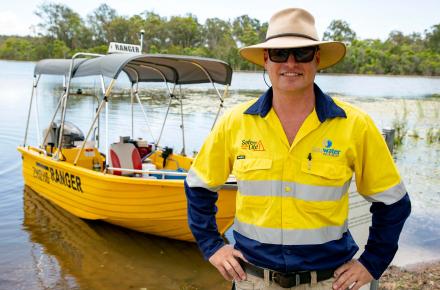 Ranger stands in front of boat