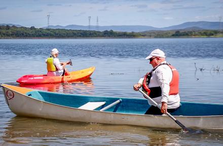 A paddler is a white canoe, and a kayaker in an orange canoe paddling on Lake Samsonvale