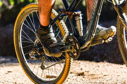 A close up shot of a mountain bike rider, with his back wheel and pedals in focus