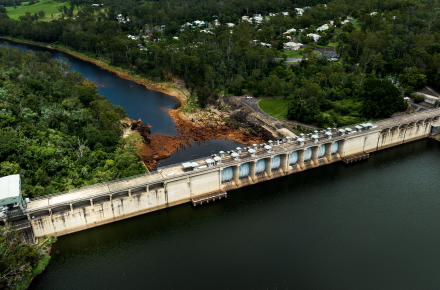 An aerial shot of the upstream side Somerset dam wall a long concrete wall holding back deep green coloured water